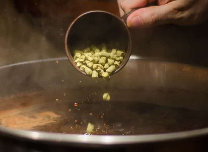 Person adding hops to batch of beer.