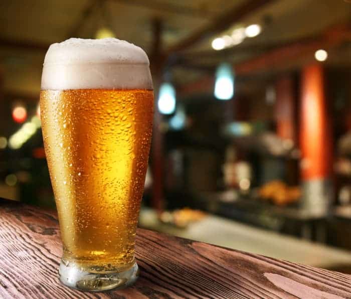 A glass of light-colored beer on a bar counter.