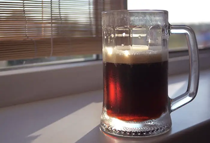 A mug of beer on a windowsill.