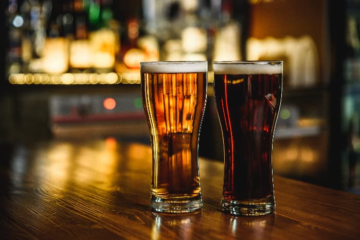Two glasses of beer on a pub bar.