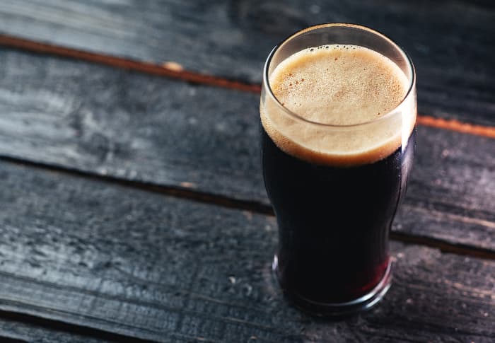 Glass of very dark beer on a pub table. Chinook hops are used to make winter beer, amber ales, stouts, and other kinds of beer.