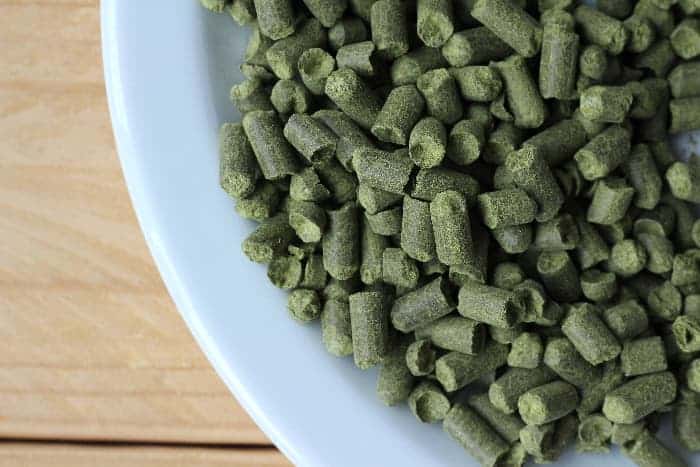 Overhead view of greenish hops pellets on plate.