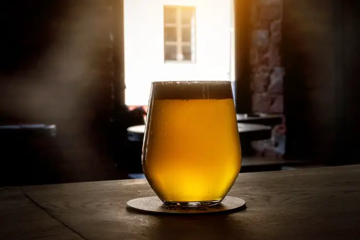 Glass of light-colored beer on the counter in a pub.  Huell hops is used for light-colored beers like Blonde Ales and IPAs.
