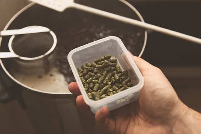 Man adding dried hops pellets to beer brew.