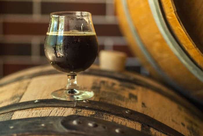 A glass of dark beer on a barrel.