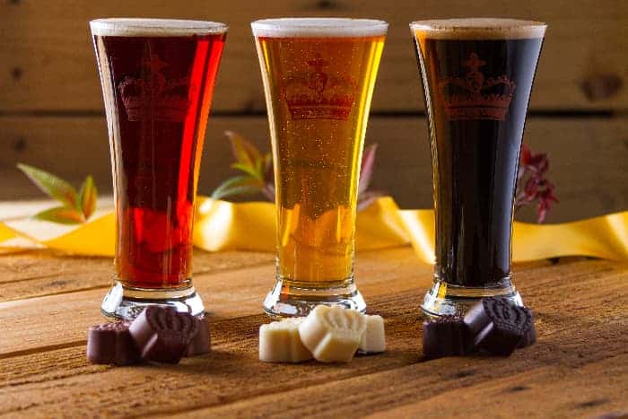 Three kinds of beer with milk, white, and dark chocolates in front of them.