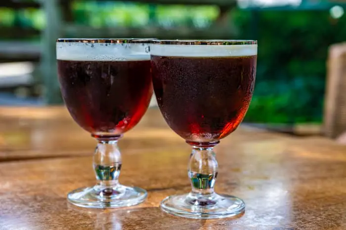 Two goblets of Belgian Abbey beer on a table outdoors.