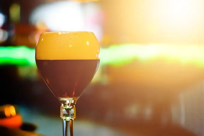 A glass of Belgian dubbel beer against sunlight.