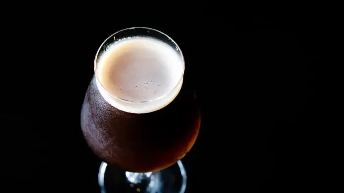 Overhead view of a goblet of Belgian dubbel beer against a black background.