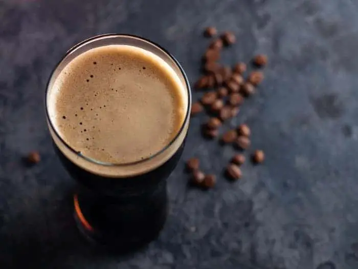 Overhead view of glass of dark coffee beer and coffee beans