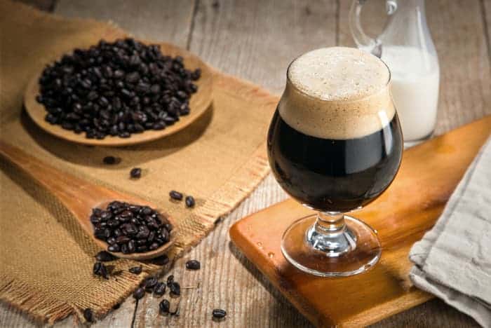A glass of dark coffee beer and coffee beans.