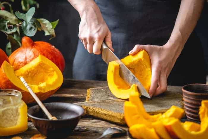 Person cutting pie pumpkins into wedges.