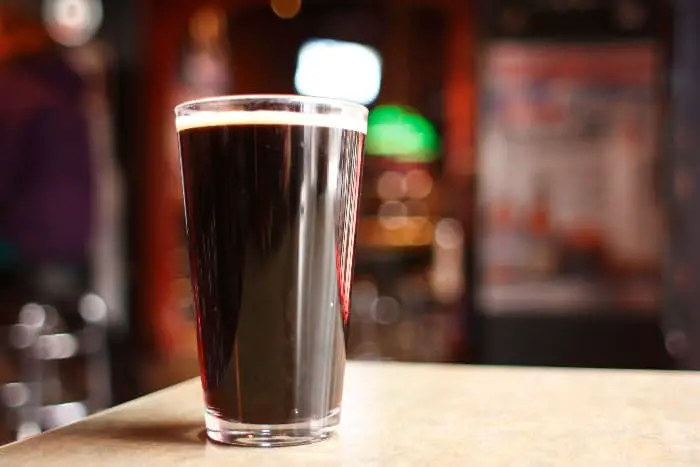 A pint glass of dark beer on a bar or pub table.