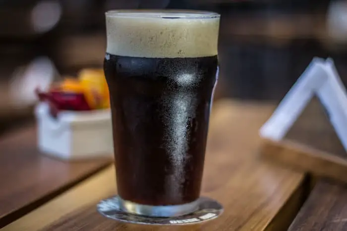A glass of dark beer in a pub or bar.