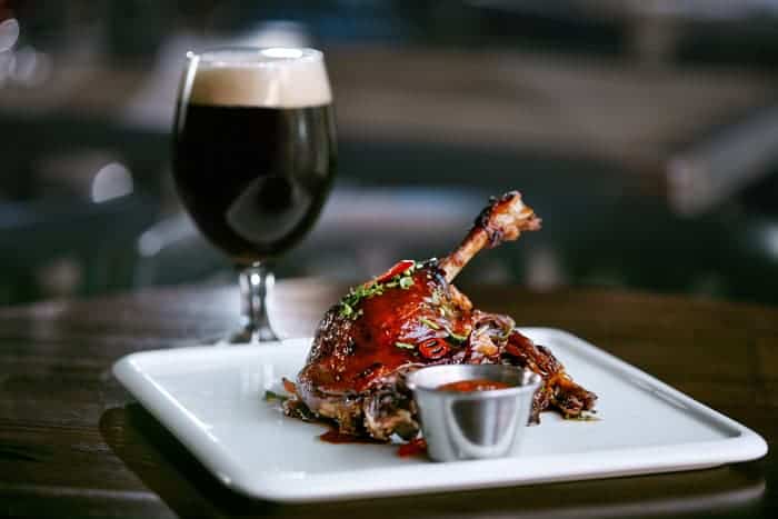 A dark beer and a plate of grilled barbecue poultry.