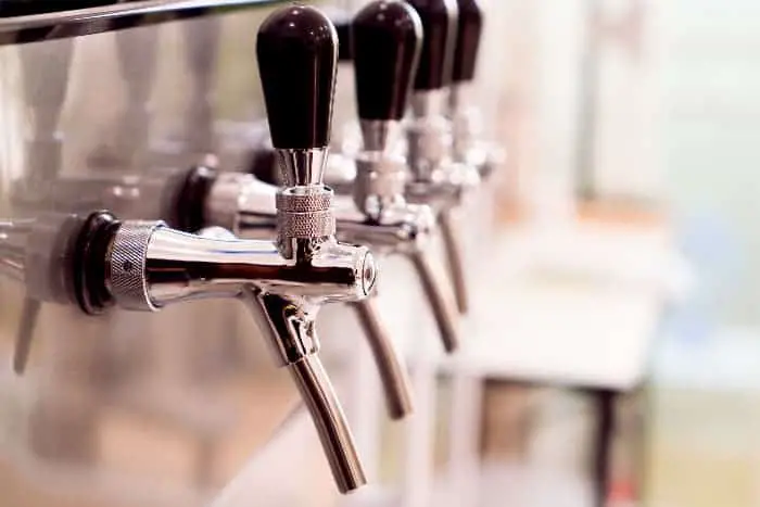 A row of stainless draft beer taps with dark handles.