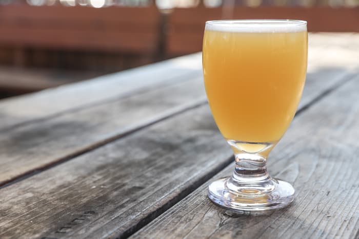 A glass of hazy IPA on a table.