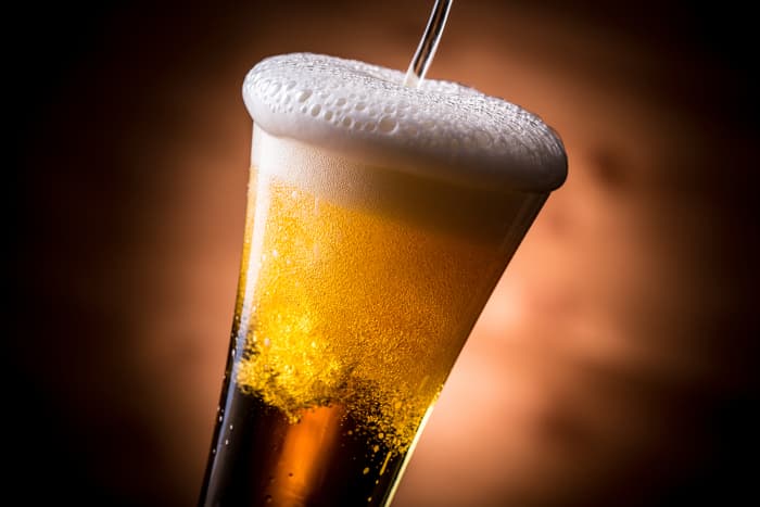 Pouring beer into a fluted beer glass.