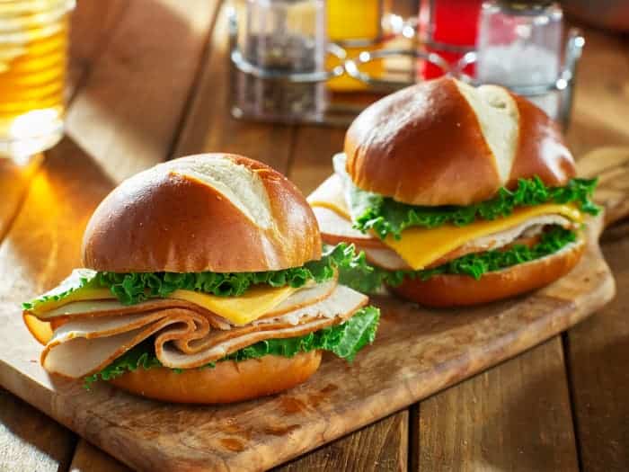 Two pub fare pretzel bun sandwiches.