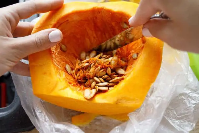 Person scraping pulp and seeds from a pie pumpkin.