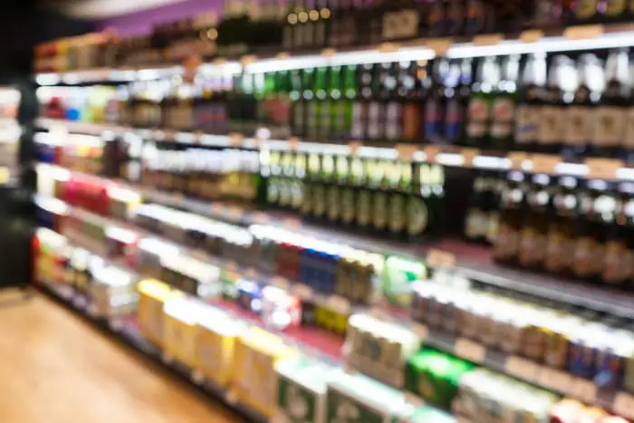 Out of focus view of bottles and cans of beer at retail store.