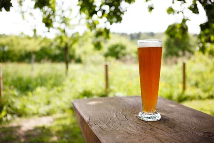 A glass of amber-colored wheat beer on an outdoor table.