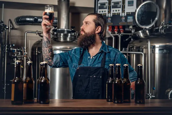 A beer brewer examining beer in a glass.
