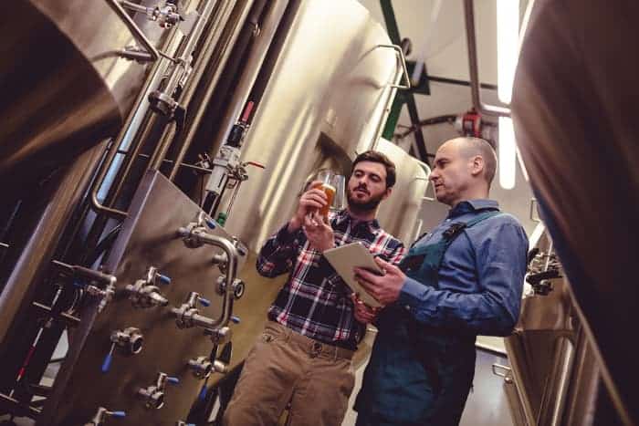 Two men having a discussion in a brewery production setting.