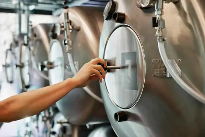Person closing the hatch of a brewing tank.