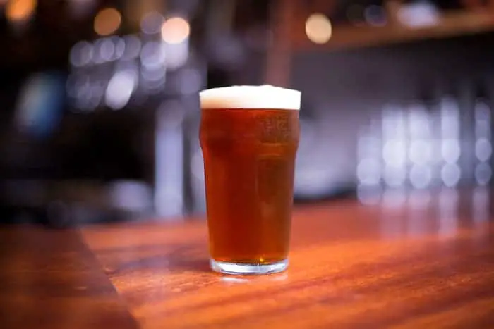 A pint of amber-colored beer on a bar.