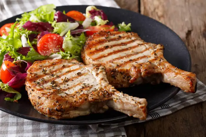 A plate of grilled pork chops and salad.