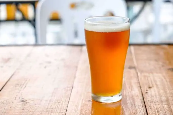 A pint glass of IPA beer on an outdoor table.
