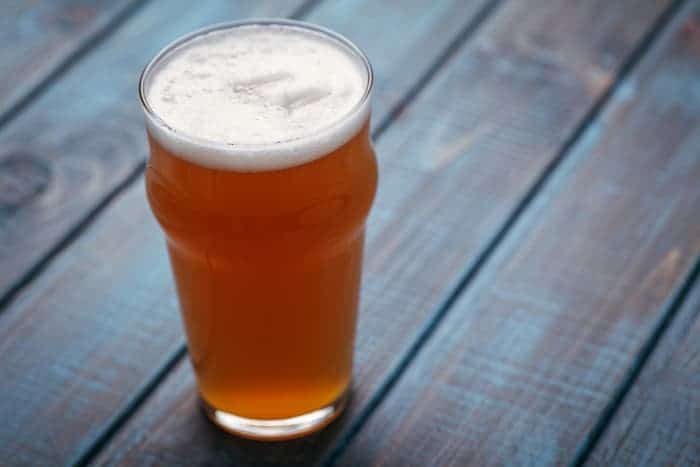 A pint glass of pale ale beer with coloring like an American IPA.