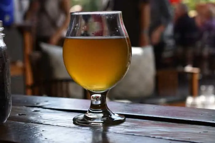 A goblet of pale ale on an outdoor table.