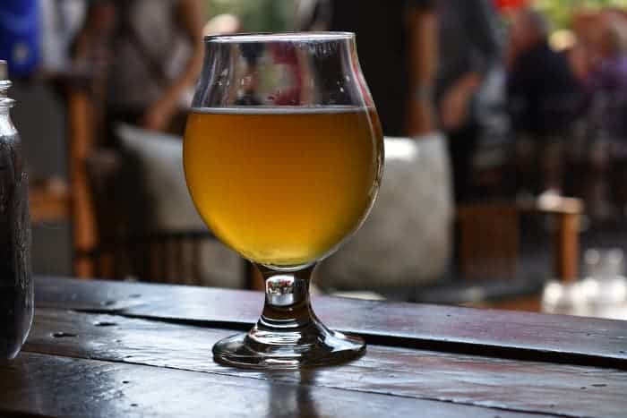 A goblet of pale ale on an outdoor table.