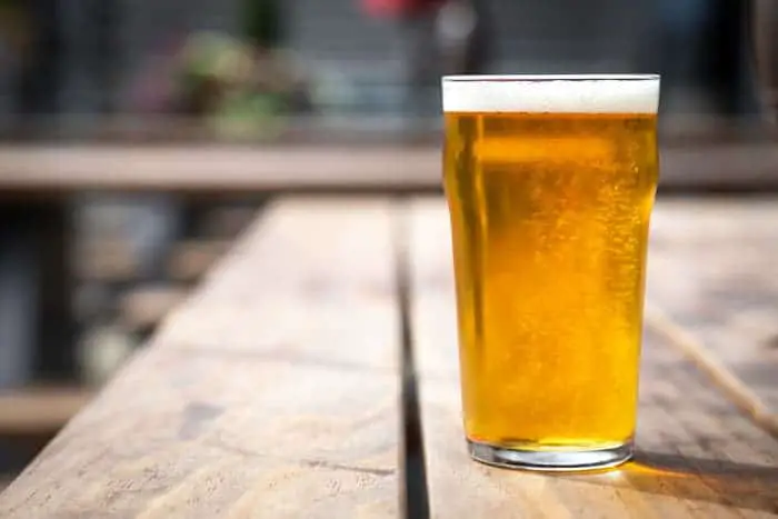 A pint glass of beer on an outdoor table.