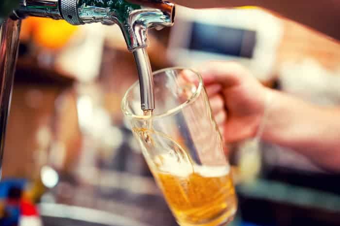 Pouring draft beer into a tall beer mug.